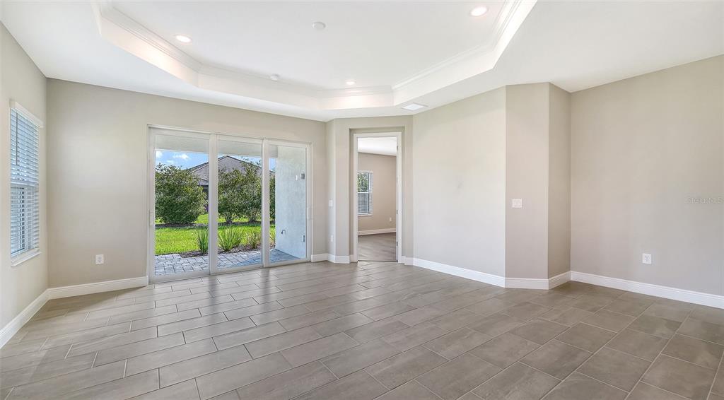 A bright room with gray tile flooring, a tray ceiling, and sliding glass doors to outdoors — 2316 BLUE MAHOE LANE, SARASOTA, FL