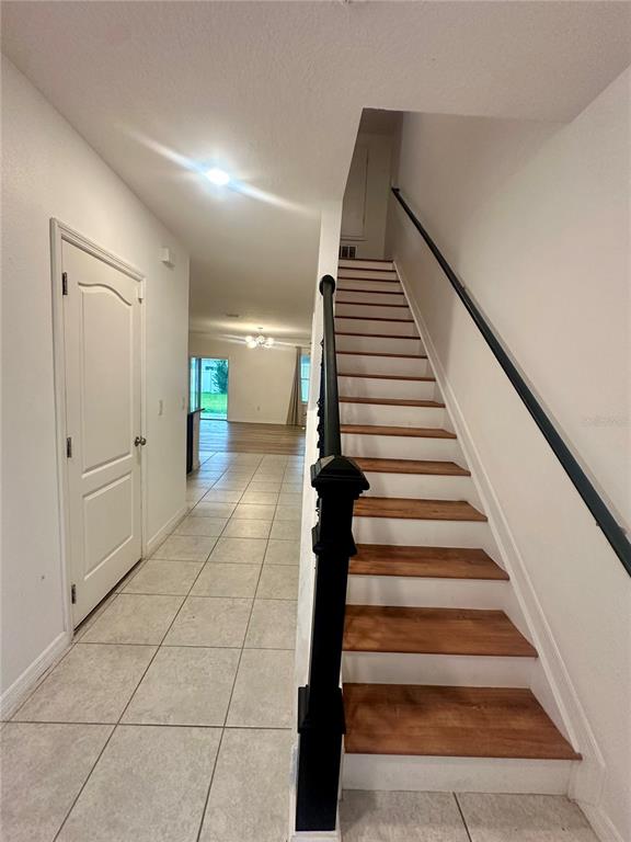 A hallway with tile flooring leads to a living area, featuring a staircase with wooden treads — 125 VILLAVISTA COURT, DAVENPORT, FL
