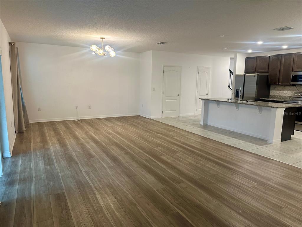 An open-concept living area features wood-look flooring, a modern chandelier, and an adjacent kitchen island — 125 VILLAVISTA COURT, DAVENPORT, FL