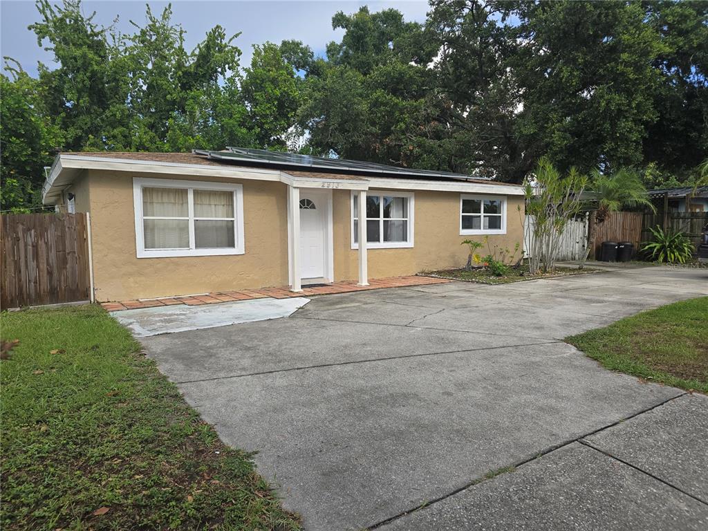 A single-story tan house with a concrete driveway and solar panels on the roof — 2913 MCINTOSH ROAD, SARASOTA, FL