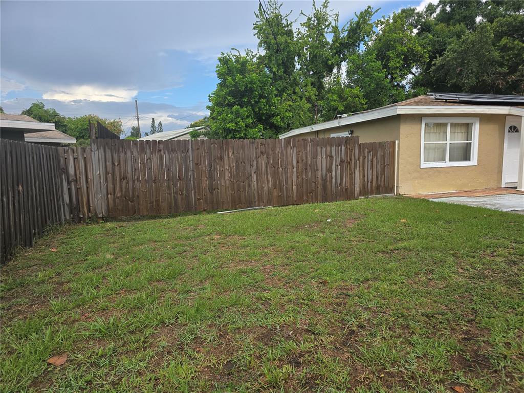 A grassy backyard features a wooden privacy fence and the side of a tan house — 2913 MCINTOSH ROAD, SARASOTA, FL