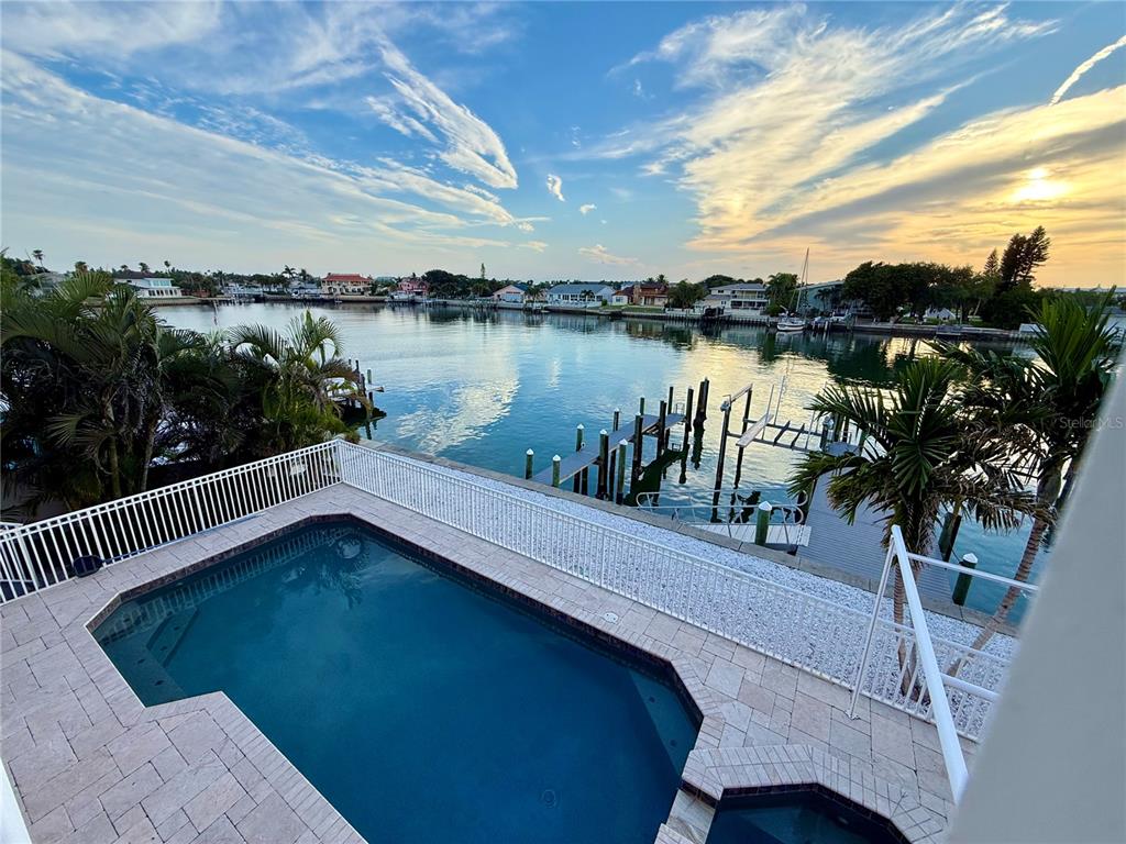 An elevated view of a swimming pool overlooking a canal with a private boat dock — 2216 DONATO DRIVE, BELLEAIR BEACH, FL