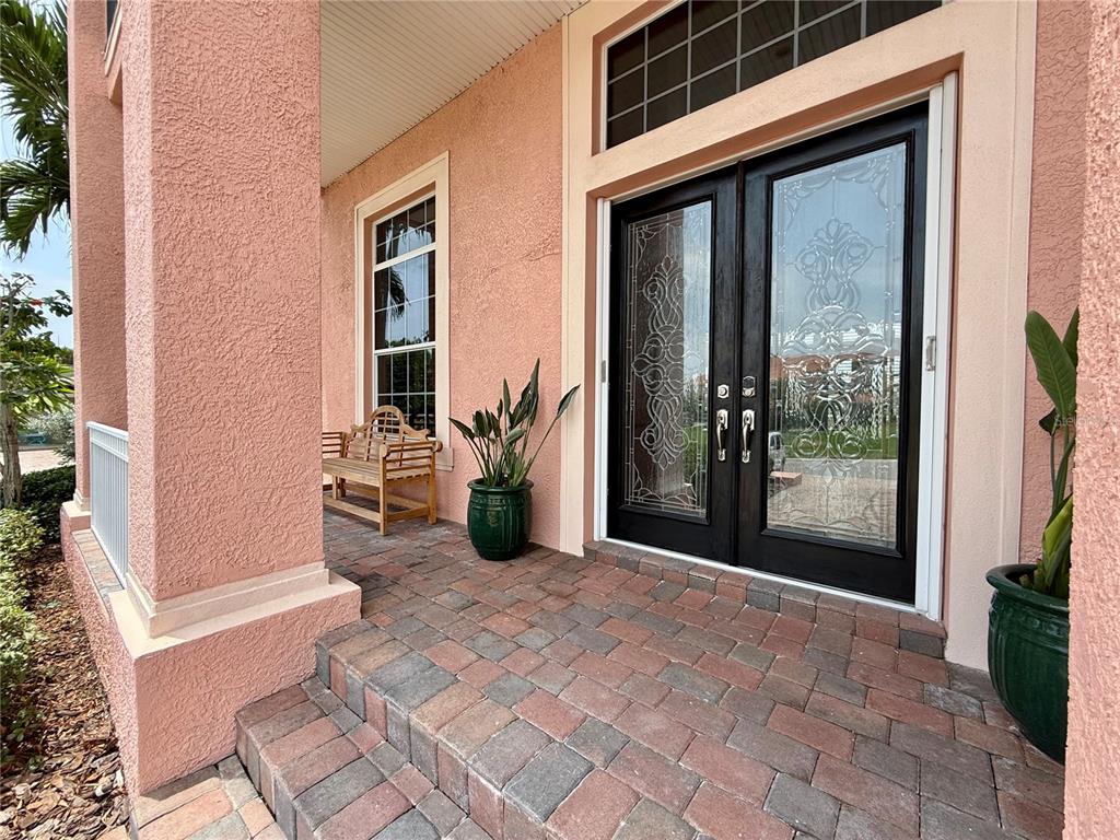 A pink stucco house exterior features a double front door with decorative glass and pavers — 2216 DONATO DRIVE, BELLEAIR BEACH, FL