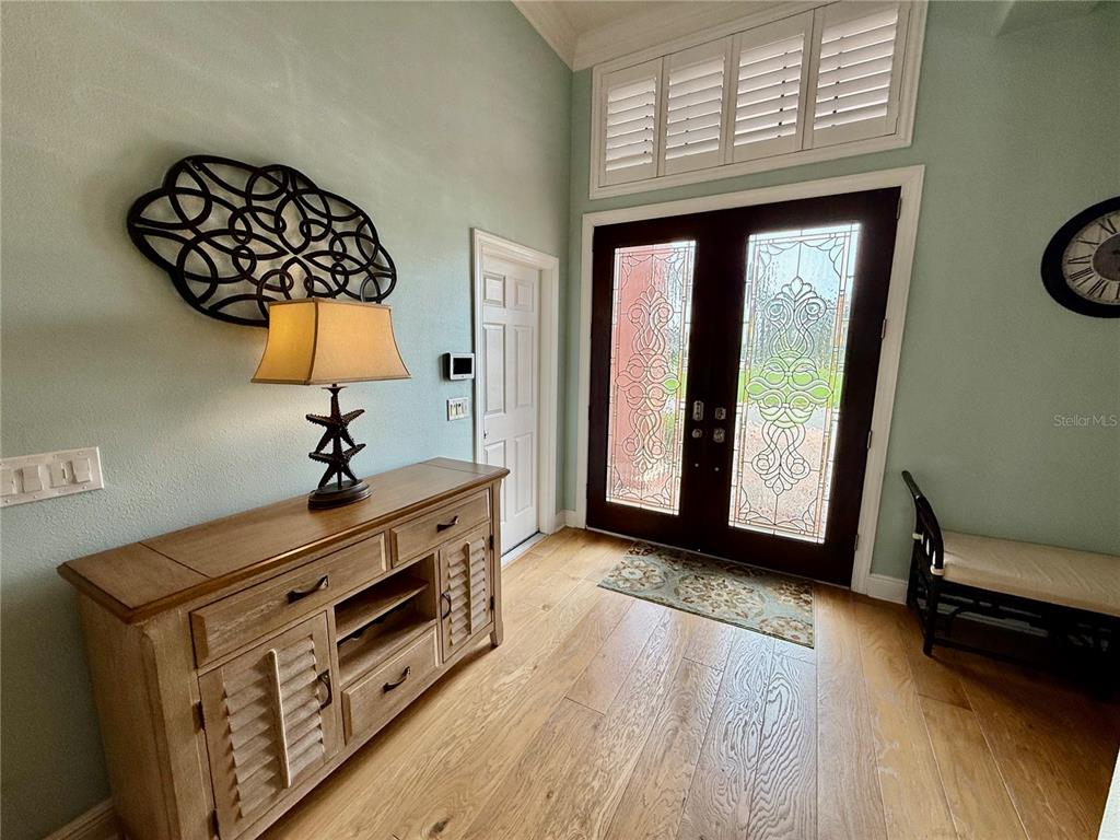 An entryway features a wooden console table, a decorative wall piece, and double glass doors — 2216 DONATO DRIVE, BELLEAIR BEACH, FL