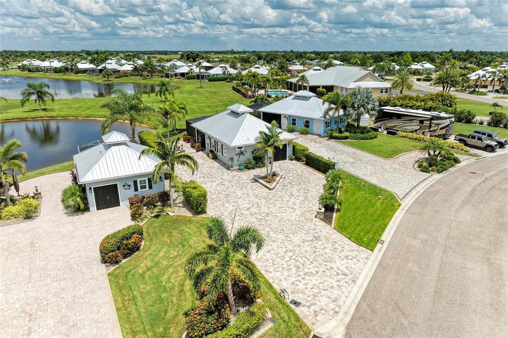 An aerial view shows three light-blue buildings with metal roofs and a large paver driveway — 8414 SW SAND CRANE CIRCLE LOT 82, ARCADIA, FL