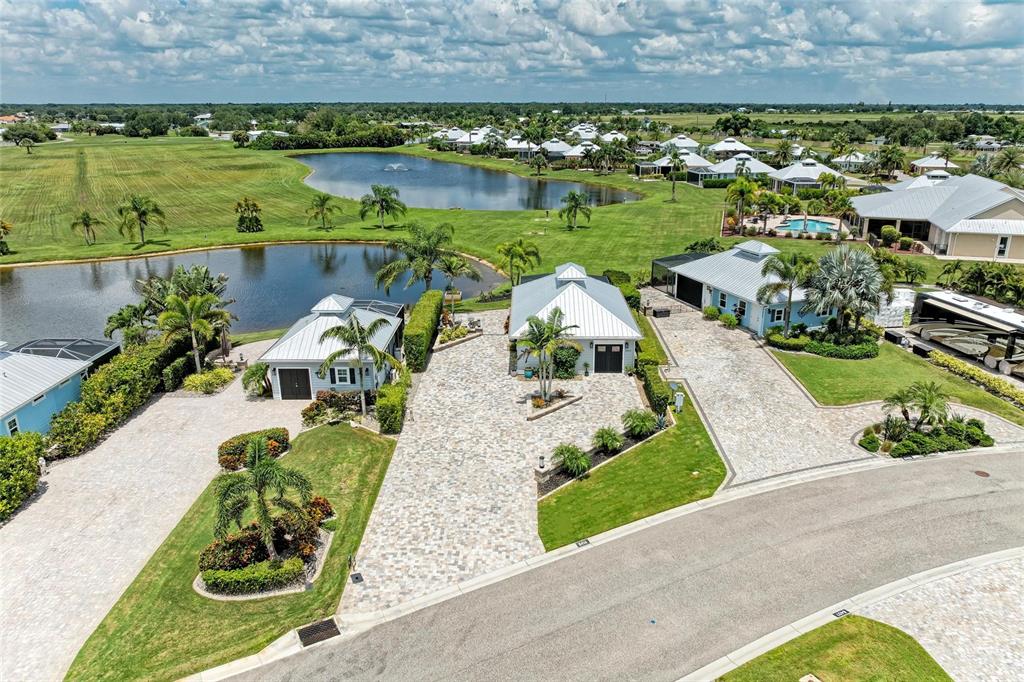 An aerial view shows three houses with metal roofs and paved driveways near ponds — 8414 SW SAND CRANE CIRCLE LOT 82, ARCADIA, FL