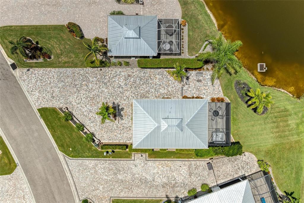An aerial view shows a house with a metal roof, paved patio, and screened lanai — 8414 SW SAND CRANE CIRCLE LOT 82, ARCADIA, FL