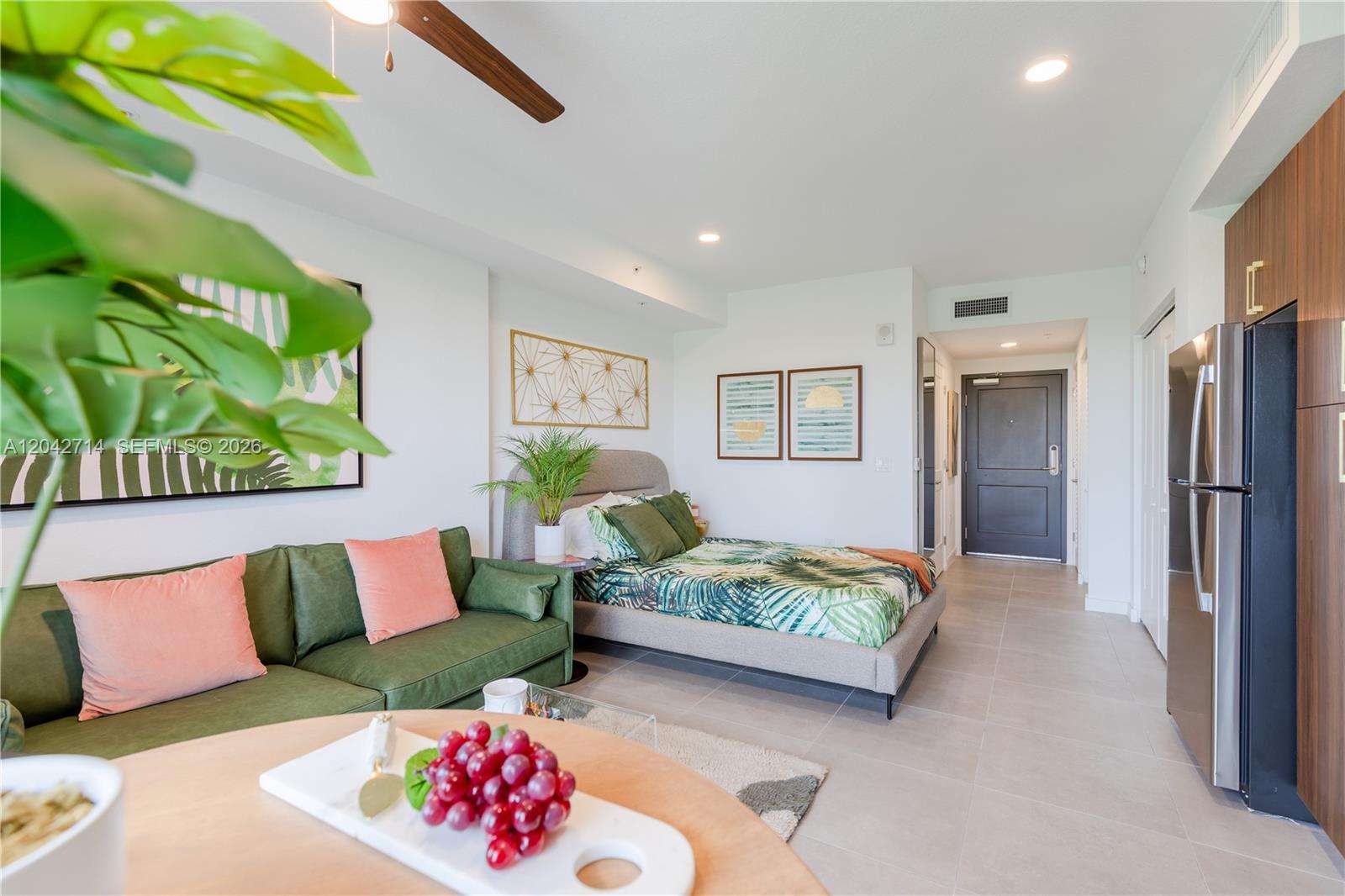 A studio apartment features a green sofa, a bed with tropical bedding, and a kitchen — 1005 Spring Garden Rd # 433, Miami FL 33136, MIAMI, FL