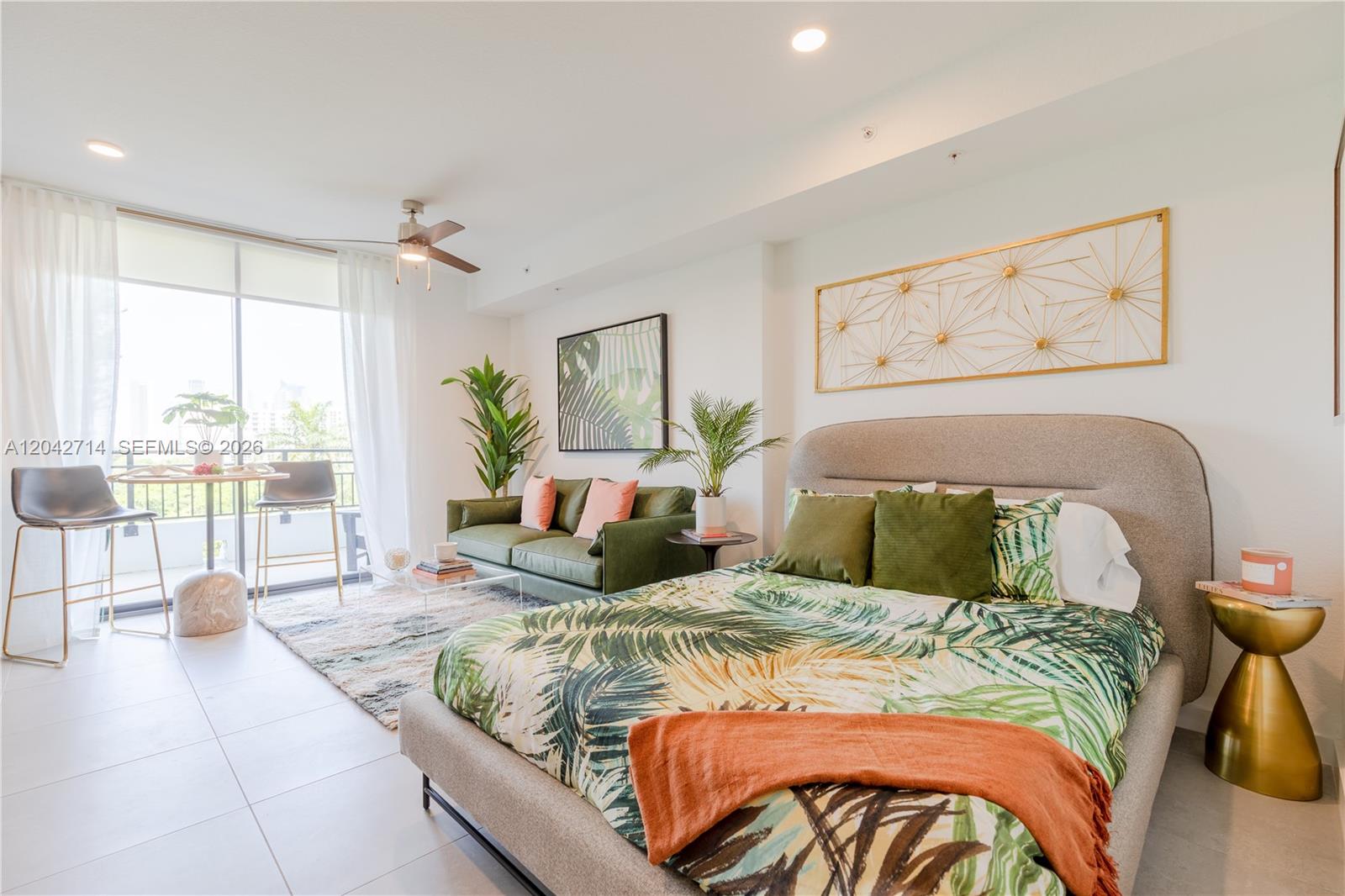 A bedroom with a bed, a green sofa, and a balcony with outdoor seating — 1005 Spring Garden Rd # 433, Miami FL 33136, MIAMI, FL