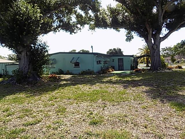 A light green single-story house sits on a grassy lot shaded by large trees — 1000 DARTMOUTH DRIVE, BRADENTON, FL