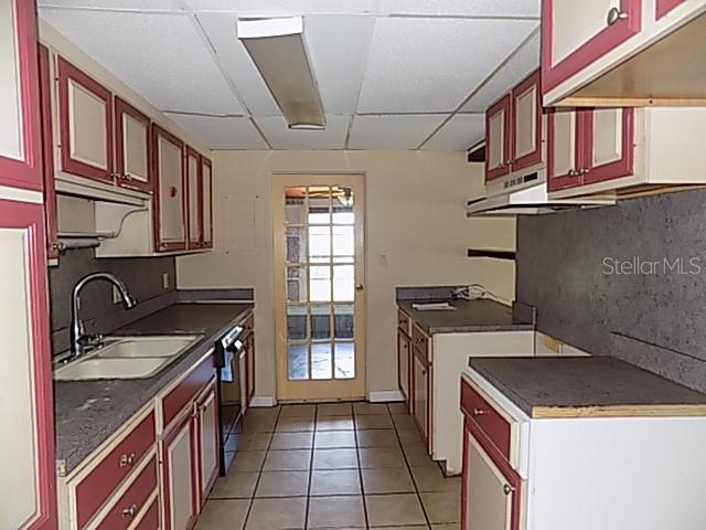 A kitchen with two-tone red and white cabinets, gray countertops, and a glass-paneled back door — 1000 DARTMOUTH DRIVE, BRADENTON, FL