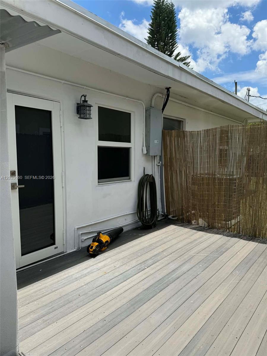 An exterior view shows a white house wall with a door, window, and wooden deck — 11100 NE 12th Ave # 0, Miami FL 33161, MIAMI, FL