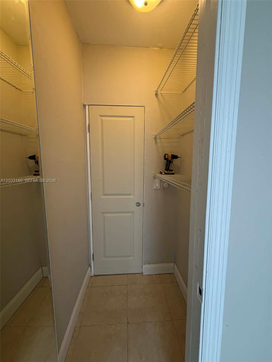 A walk-in closet features white wire shelving, a tiled floor, and a mirrored wall — 11100 NE 12th Ave # 0, Miami FL 33161, MIAMI, FL