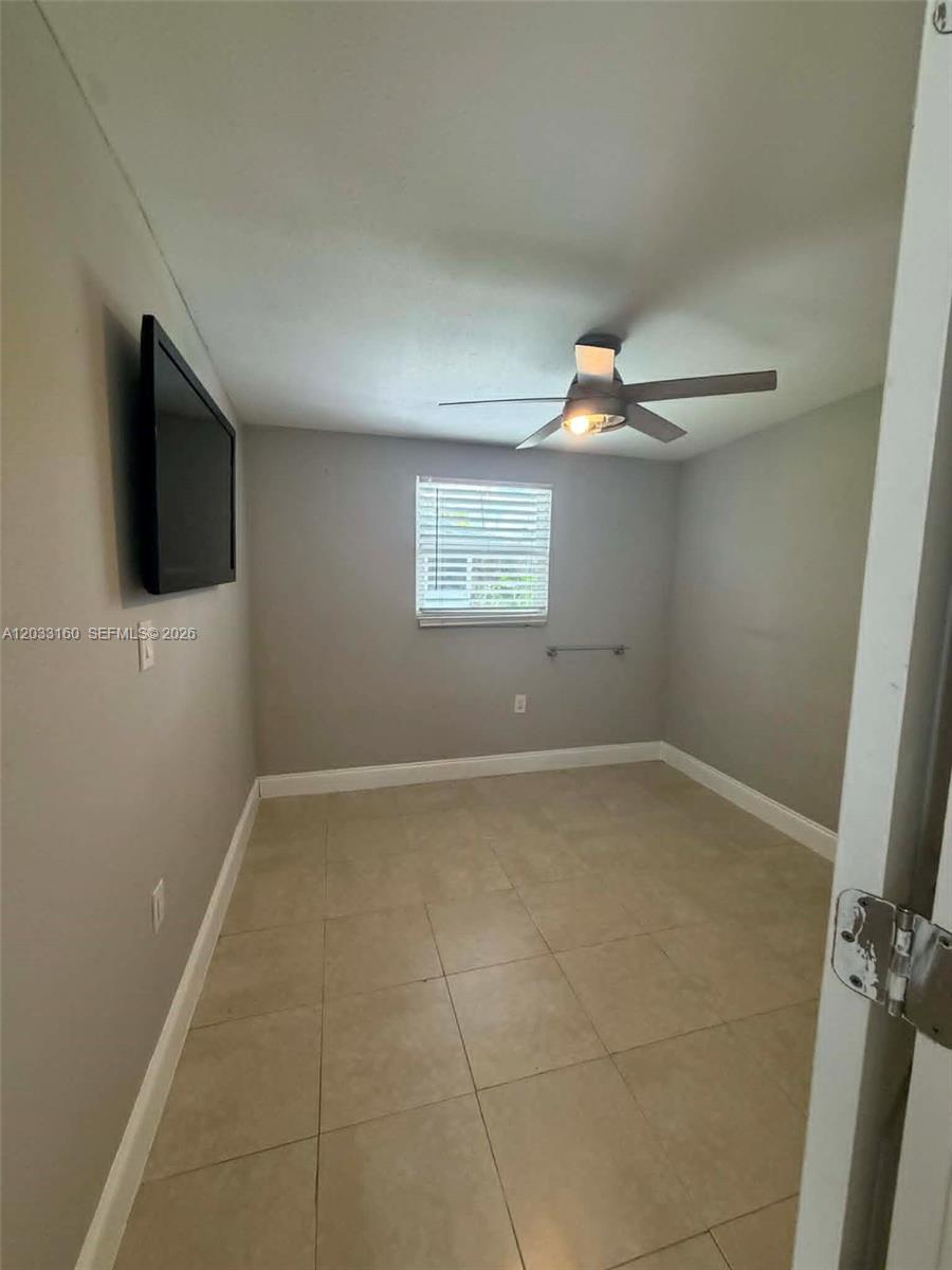 A small, empty room features light-colored tile flooring, gray walls, and a ceiling fan — 11100 NE 12th Ave # 0, Miami FL 33161, MIAMI, FL