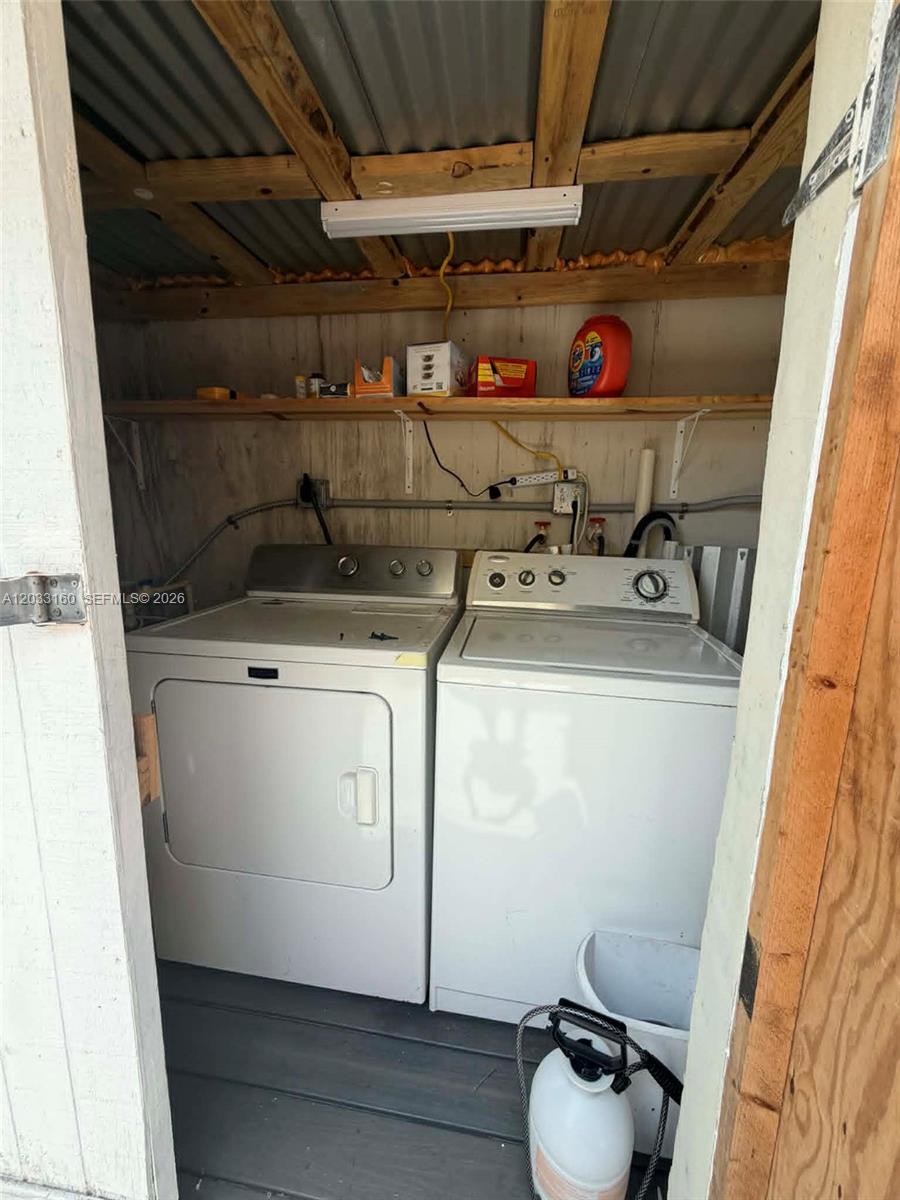 A laundry area features a washer and dryer beneath a wooden shelf with supplies — 11100 NE 12th Ave # 0, Miami FL 33161, MIAMI, FL