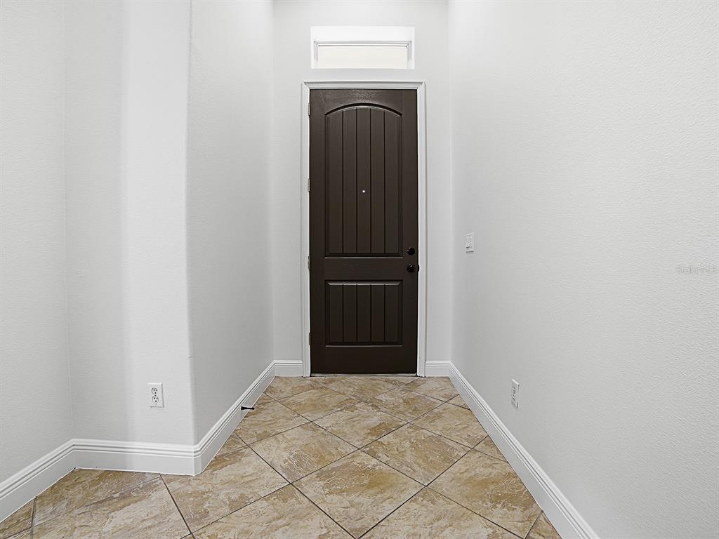 An entryway features a dark brown door, white walls, and light-colored diagonal tile flooring — 1404 CARING COURT, MAITLAND, FL