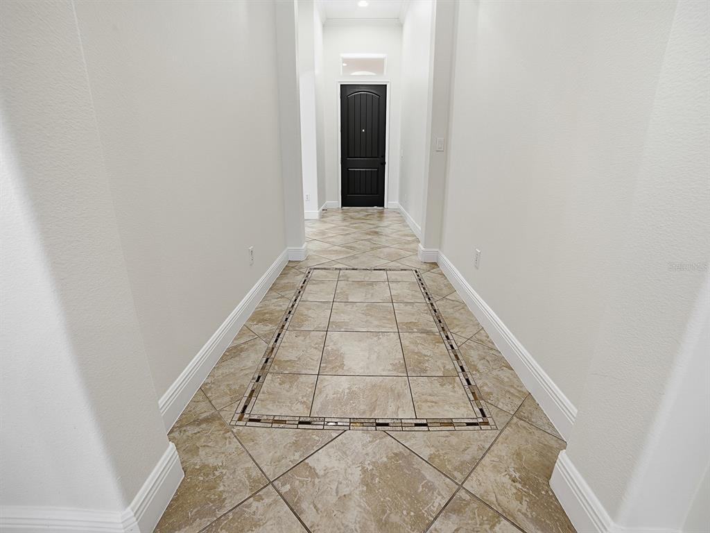 A hallway features light-colored walls, white baseboards, and tile flooring with a decorative border — 1404 CARING COURT, MAITLAND, FL