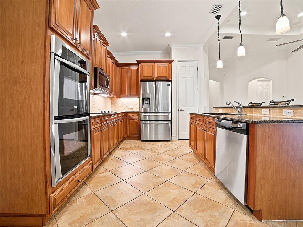 A kitchen features wood cabinets, stainless steel appliances, granite countertops, and diagonal tile flooring — 1404 CARING COURT, MAITLAND, FL