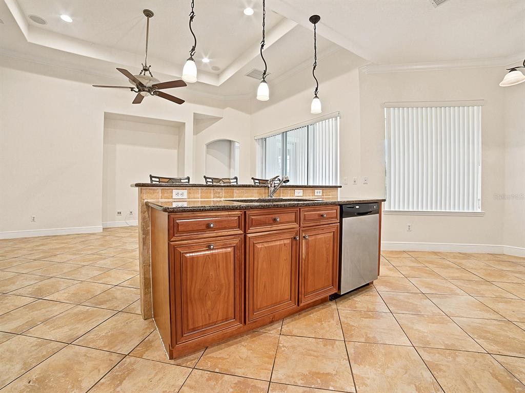 A kitchen island with wood cabinets and a granite countertop sits on a tiled floor — 1404 CARING COURT, MAITLAND, FL