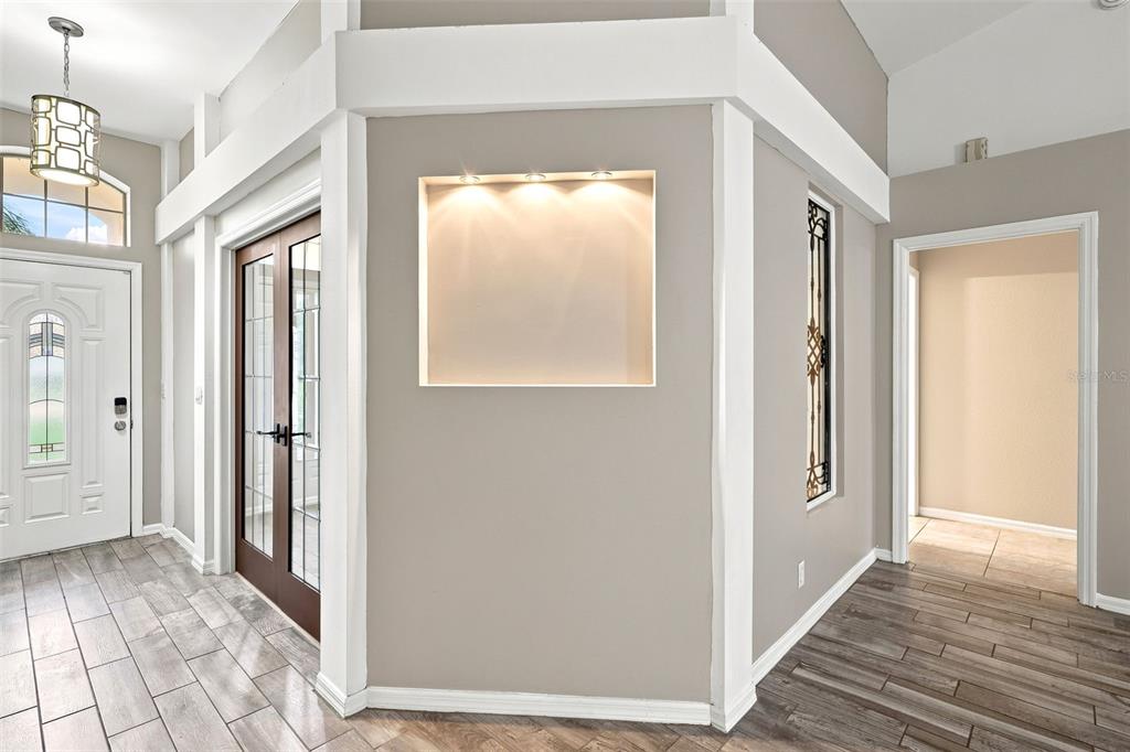 An entryway features a recessed wall niche with lighting, wood-framed glass doors, and tile flooring — 521 TACOMA AVENUE, DELTONA, FL