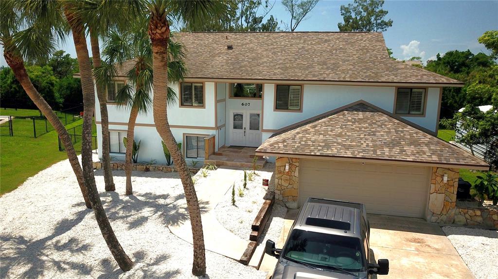 An aerial view of a two-story house with a light blue exterior and shingled roof — 607 IXORA AVENUE, ELLENTON, FL