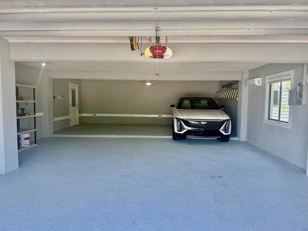 A spacious garage features a gray epoxy floor, a white car, and a ceiling-mounted opener — 607 IXORA AVENUE, ELLENTON, FL