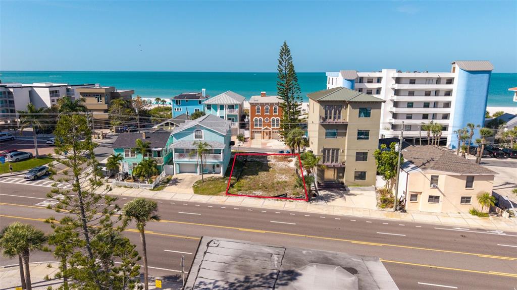 An aerial view shows a vacant rectangular lot situated between two houses near the ocean — 13304 GULF BOULEVARD, MADEIRA BEACH, FL