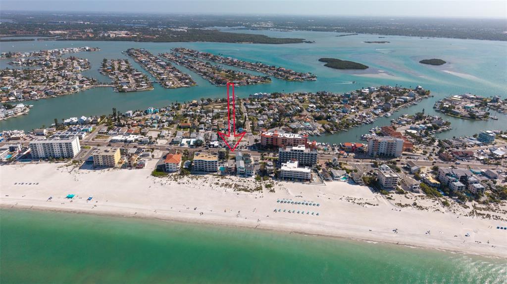 Aerial view of a beach town with a red arrow pointing toward a specific property — 13304 GULF BOULEVARD, MADEIRA BEACH, FL