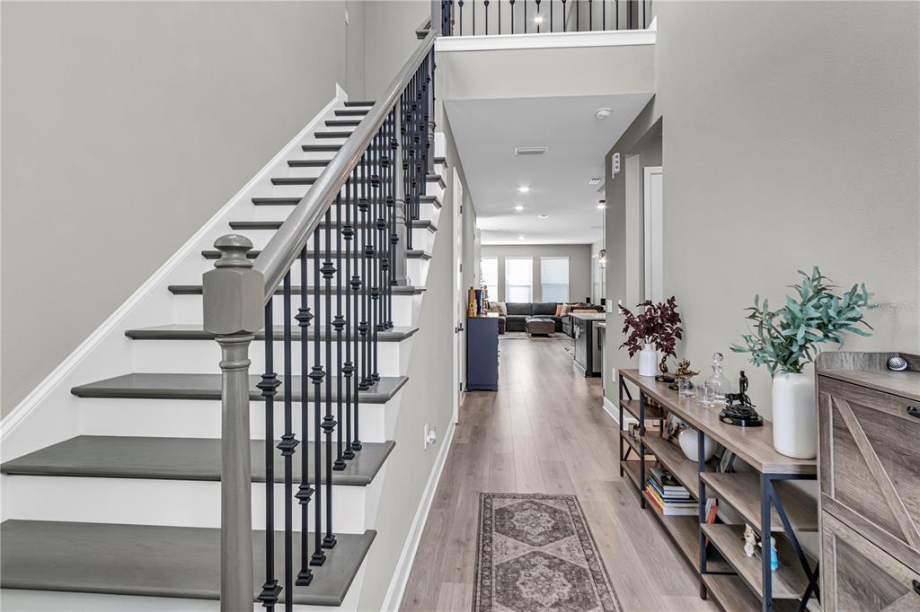 A staircase with dark wood treads and black iron railings leads to a second-floor landing — 16271 HONEY HARVEST STREET, WINTER GARDEN, FL