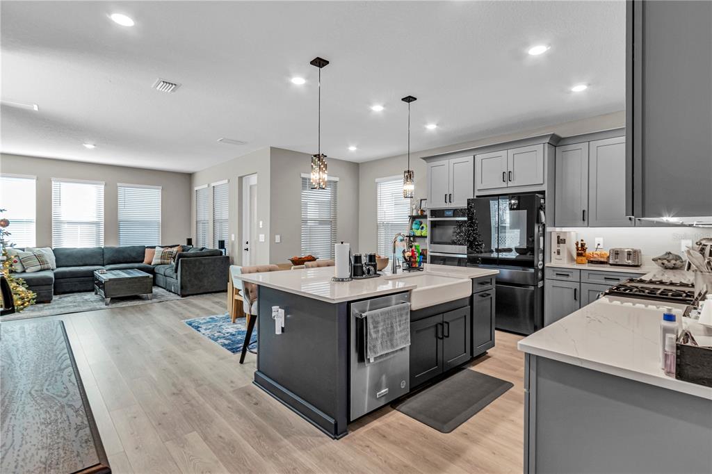 A kitchen with a dark island and white countertops opens into a living room area — 16271 HONEY HARVEST STREET, WINTER GARDEN, FL