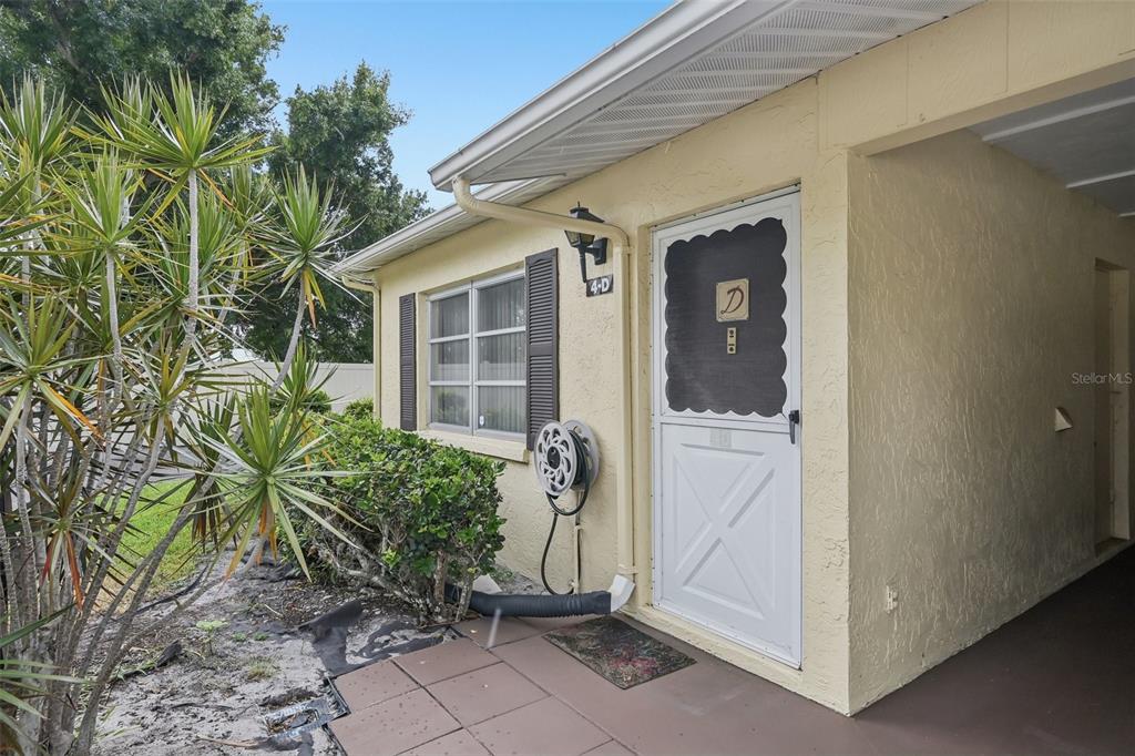 A tan exterior wall features a white storm door, a window, and a hose reel — 390 301 BOULEVARD W UNIT 4D, BRADENTON, FL