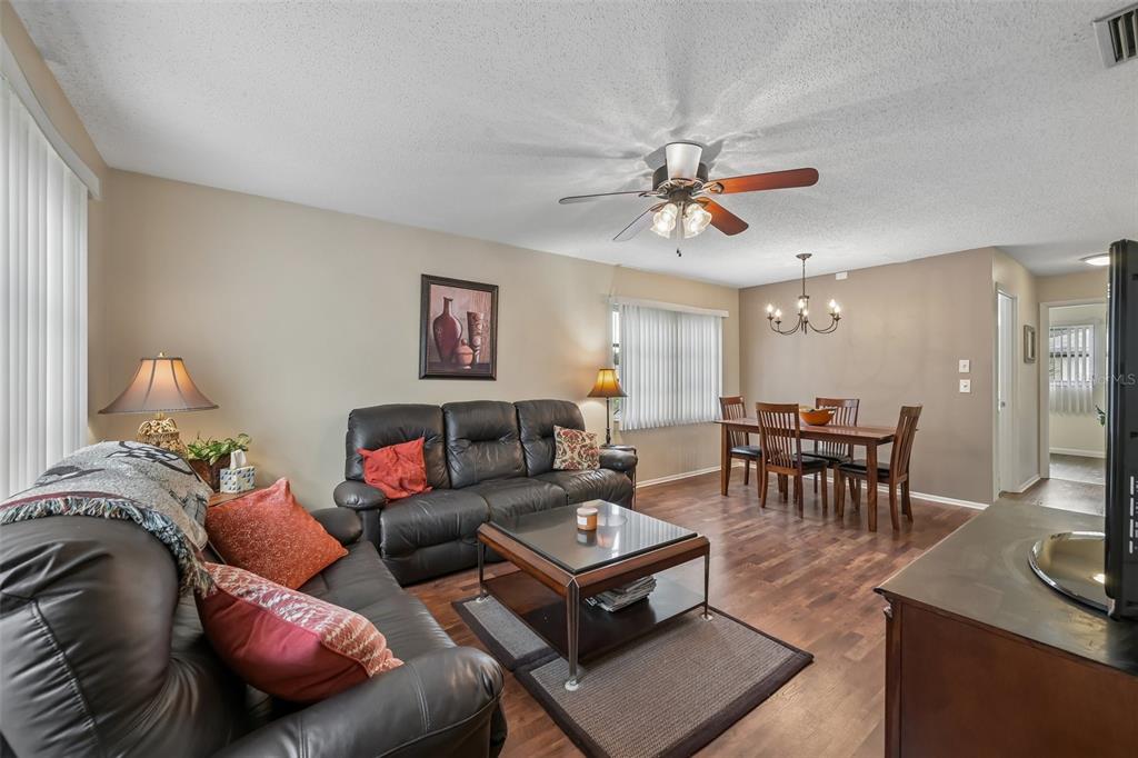 A living and dining room with dark leather sofas, a glass coffee table, and wood flooring — 390 301 BOULEVARD W UNIT 4D, BRADENTON, FL