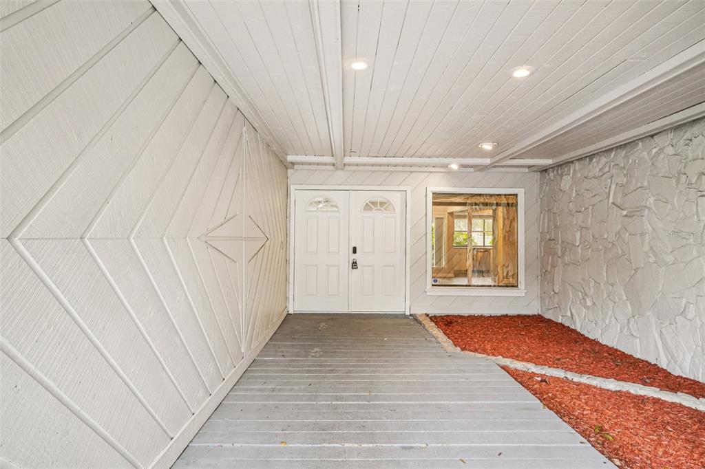 A covered entryway features a white double door, wood-paneled ceiling, and a stone accent wall — 4218 WATER OAKS LANE, TAMPA, FL