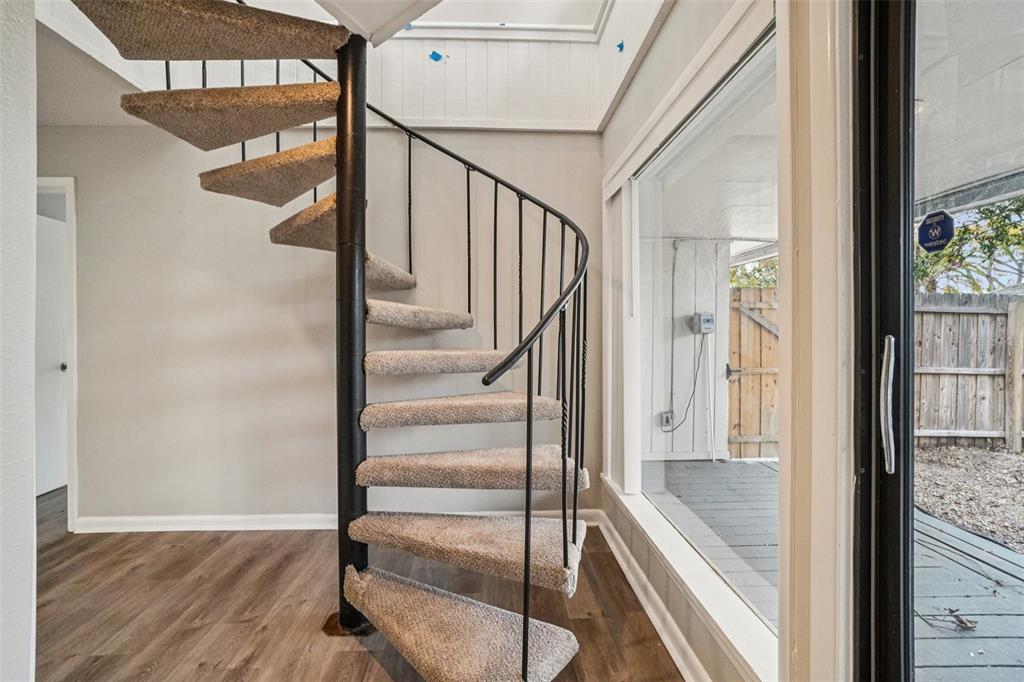 A carpeted spiral staircase stands in a room with wood-look flooring and a sliding glass door — 4218 WATER OAKS LANE, TAMPA, FL