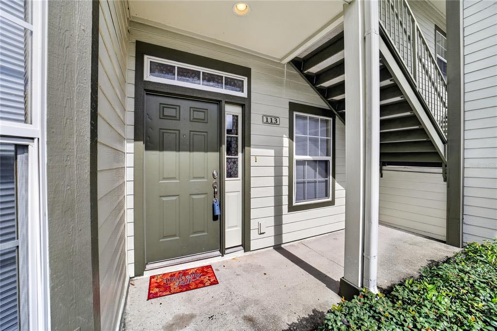 The exterior entrance of a residential unit features a green door, a window, and stairs — 2935 NE 7TH STREET UNIT 113, OCALA, FL