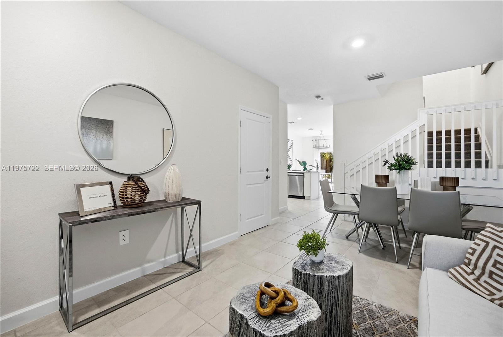 A modern living and dining area features a console table, mirror, and staircase — 13074 SW 233rd Ter, Homestead FL 33032, HOMESTEAD, FL
