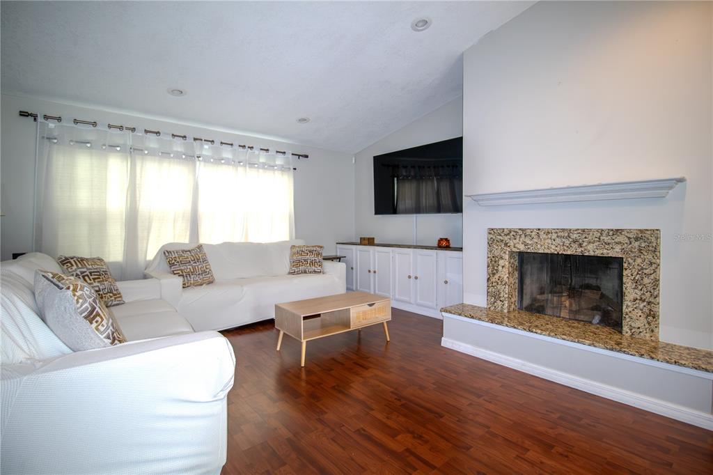 A living room features white sofas, a wooden coffee table, a fireplace, and built-in cabinets — 103 CASHEW COURT, LONGWOOD, FL