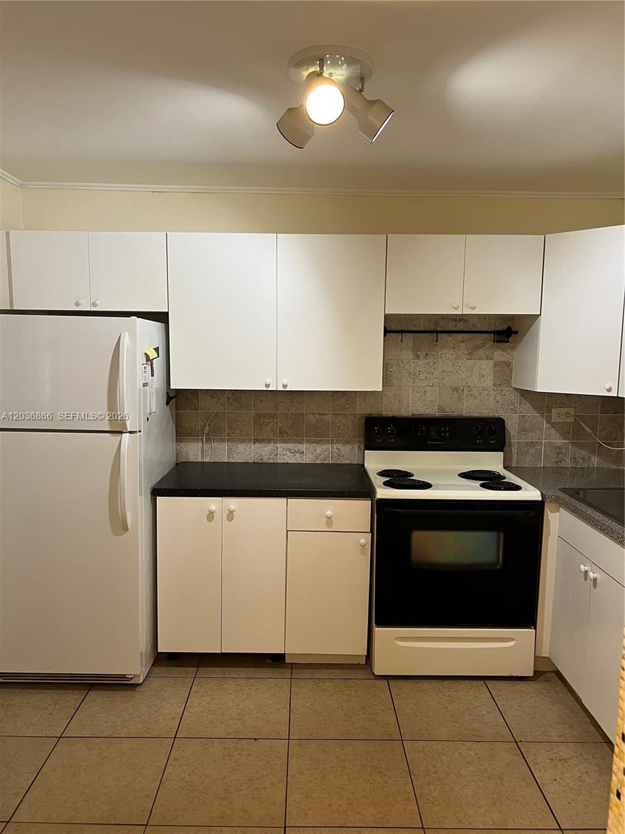 A kitchen features white cabinets, a black countertop, a white stove, and a white refrigerator — 1680 NE 191st St # 2, Miami FL 33179, MIAMI, FL