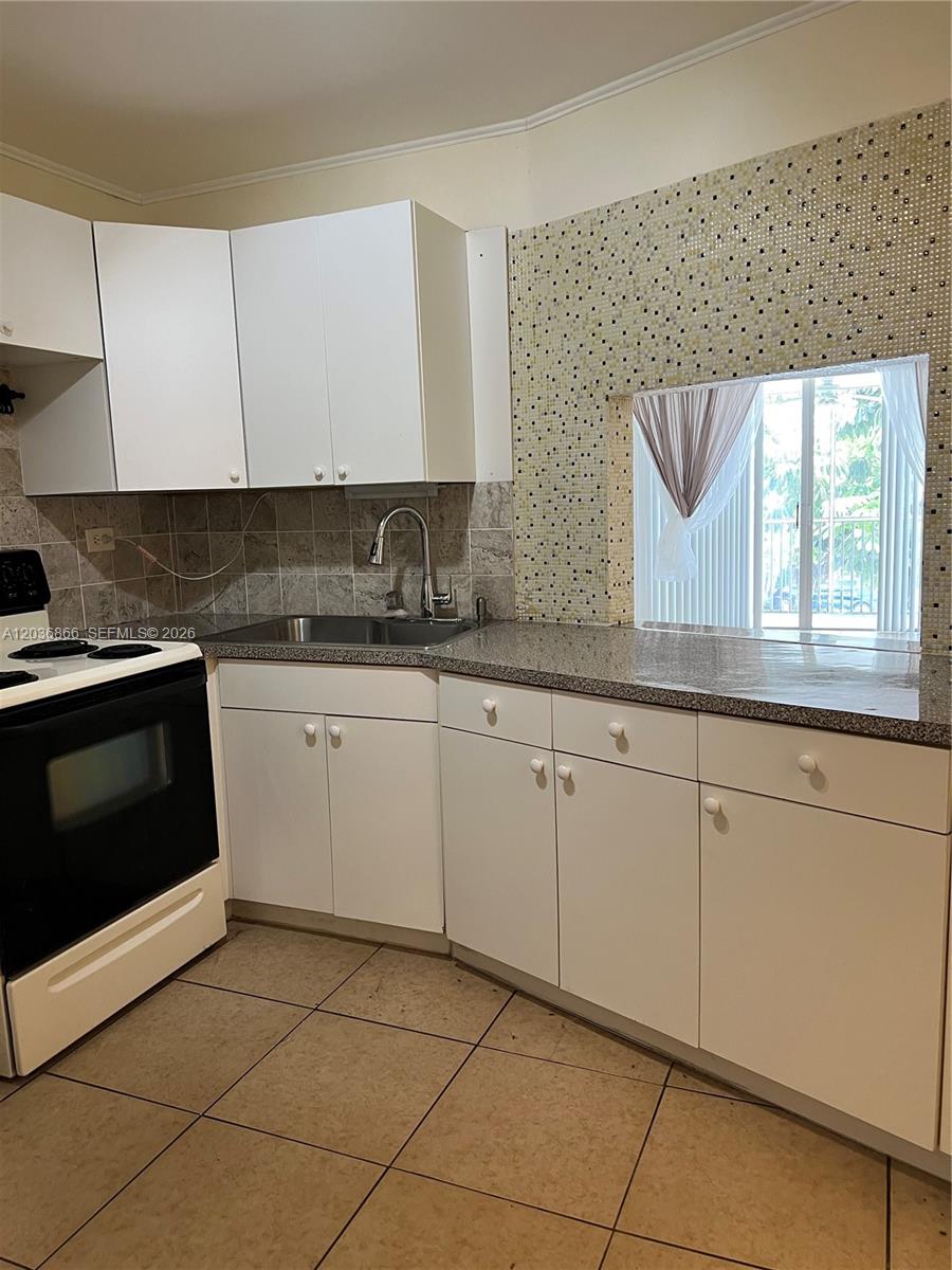 A kitchen features white cabinets, a granite countertop, a tile backsplash, and a window — 1680 NE 191st St # 2, Miami FL 33179, MIAMI, FL