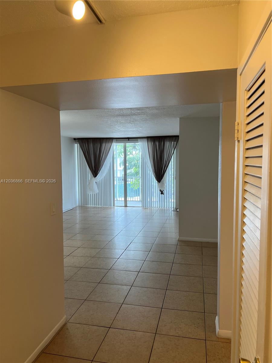 A tiled living area features a sliding glass door with curtains leading to a balcony — 1680 NE 191st St # 2, Miami FL 33179, MIAMI, FL