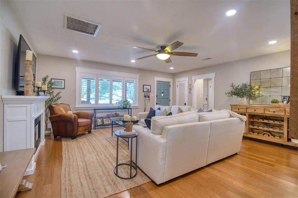 A living room features a white fireplace, a beige sofa, a leather armchair, and hardwood floors — 128 EDGEWATER TERRACE, DUNEDIN, FL