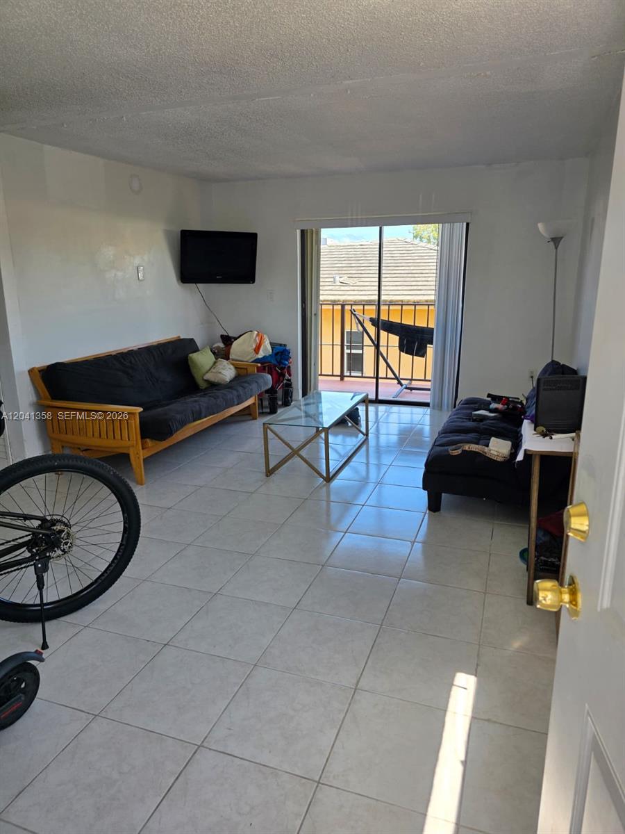 A living room features tile flooring, two sofas, a glass coffee table, and a balcony — 990 Biarritz Dr # 303, Miami Beach FL 33141, MIAMI BEACH, FL