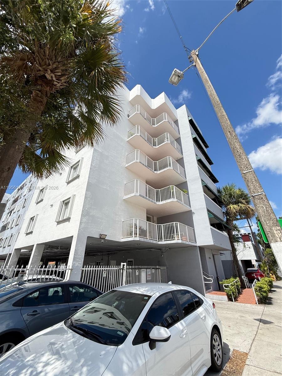 A white multi-story apartment building features stacked balconies and a ground-level parking area — 4854 NW 7th St # 508, Miami FL 33126, MIAMI, FL