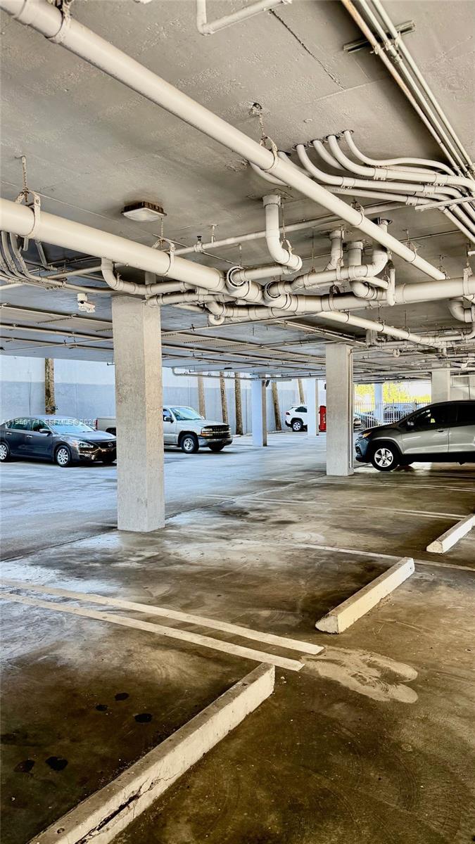 A concrete parking garage features exposed overhead pipes and support columns — 4854 NW 7th St # 508, Miami FL 33126, MIAMI, FL