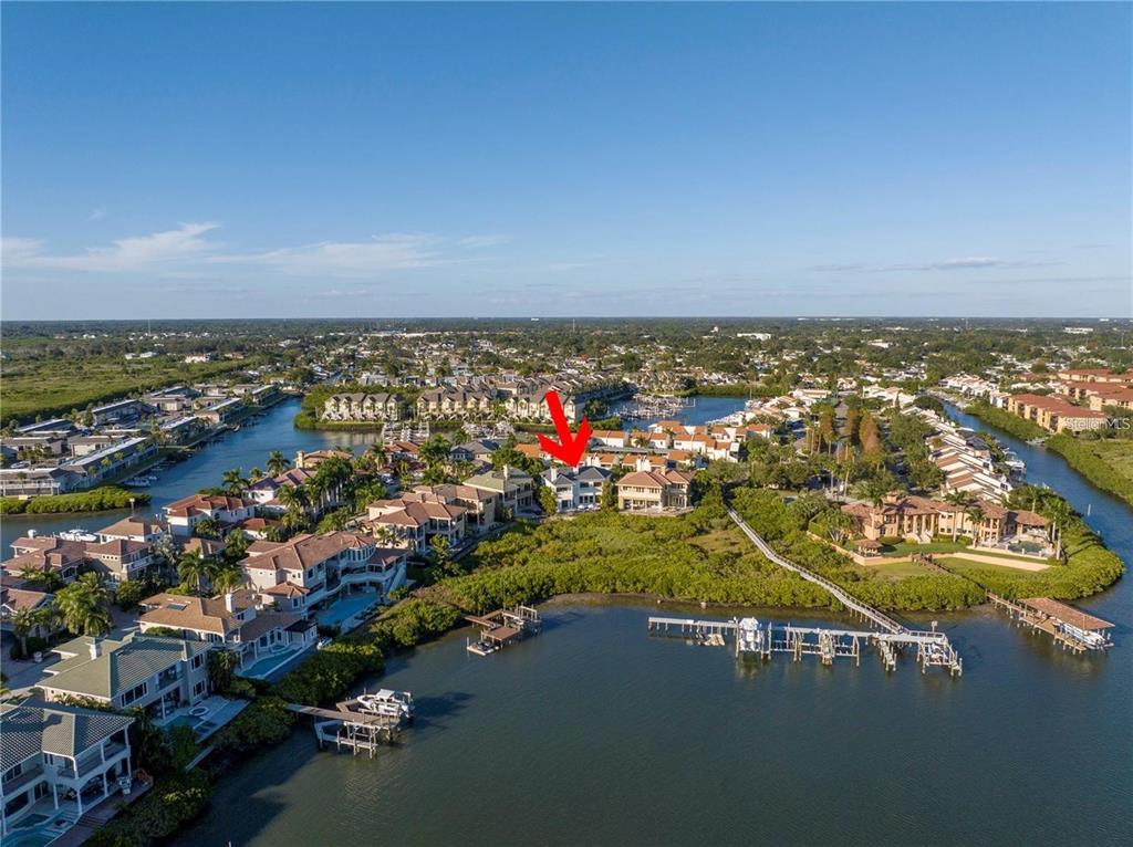 An aerial view shows a waterfront residential neighborhood with a red arrow pointing to a house — 4133 CAUSEWAY VISTA DRIVE, TAMPA, FL