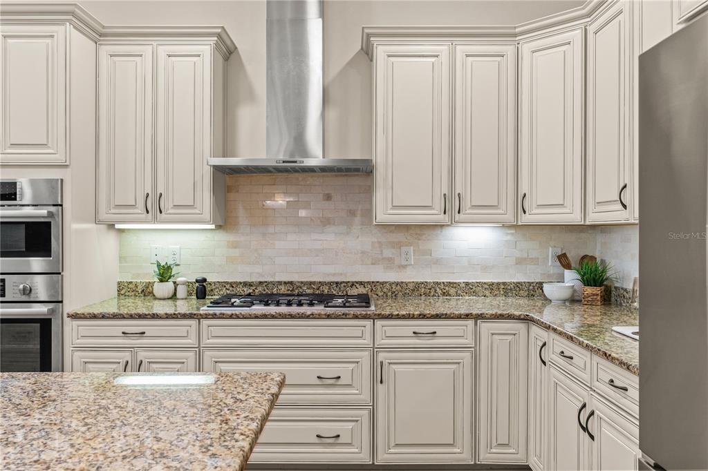A kitchen with cream cabinets, granite countertops, a stainless steel range hood, and tile backsplash — 606 S LINCOLN AVENUE UNIT 2, TAMPA, FL