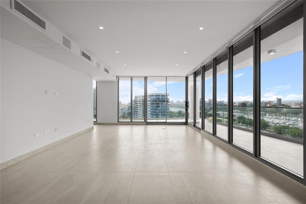 An empty room with large floor-to-ceiling windows, light tile flooring, and a balcony view — 540 DE LA CONSTITUCION AVENUE UNIT 1202, SAN JUAN, PR
