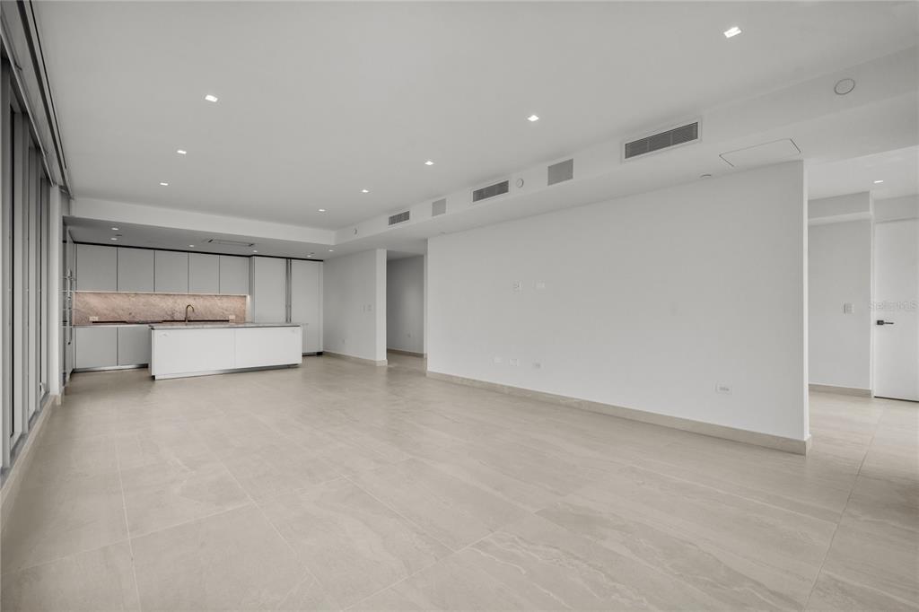 A modern, open-concept living area features a kitchen with white cabinetry and large floor tiles — 540 DE LA CONSTITUCION AVENUE UNIT 1202, SAN JUAN, PR