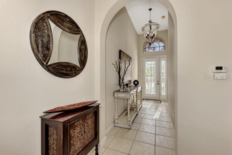 A tiled entryway features an arched opening, a console table, and a decorative wall mirror — 13099 PRESERVE COURT, PORT CHARLOTTE, FL