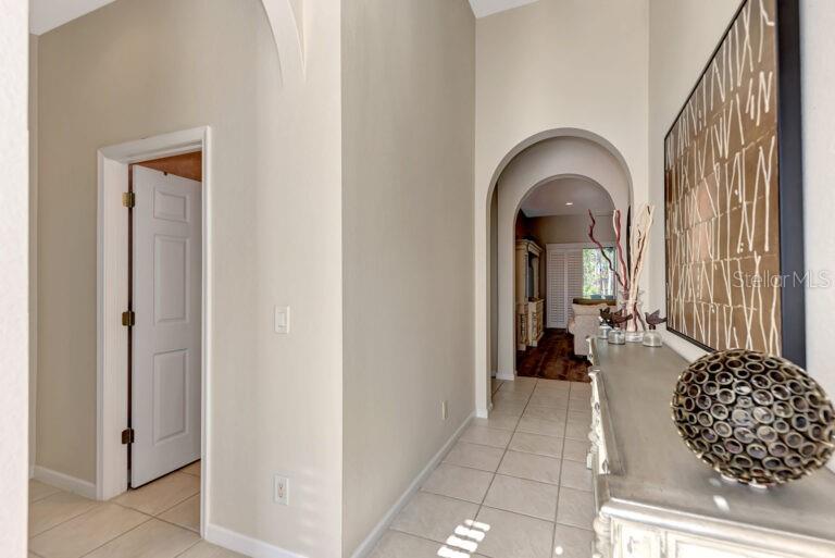 A hallway with tile flooring leads through an arched doorway toward a living area — 13099 PRESERVE COURT, PORT CHARLOTTE, FL